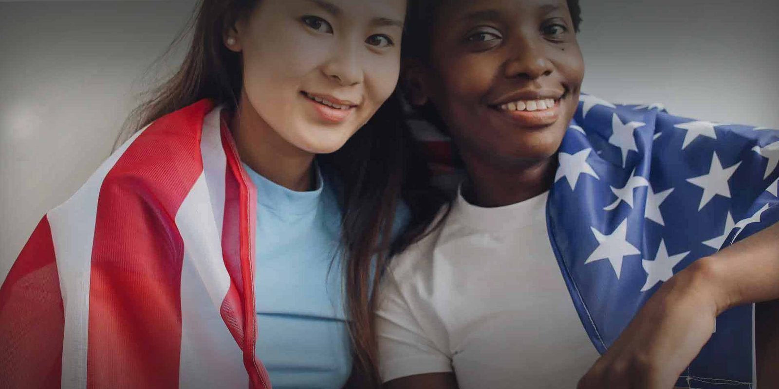 Two young women proudly displaying American flags on their shoulders for a patriotic blog.