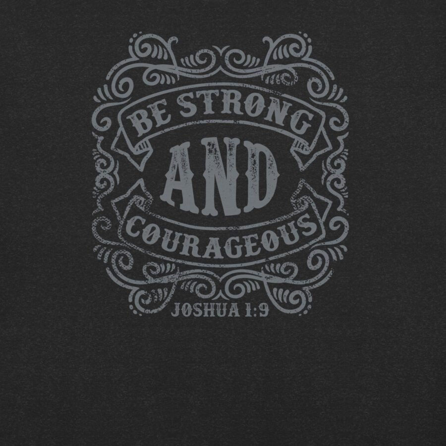 The BE STRONG AND COURAGEOUS | Unisex T-shirt features ornate text on a dark background boldly proclaiming "BE STRONG AND COURAGEOUS, Joshua 1:9" with striking detail. This piece is both an inspirational and timeless statement of faith suitable for any wardrobe.